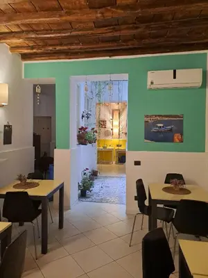 a dining room with two tables and chairs and a kitchen at Ai Tintori in Palermo
