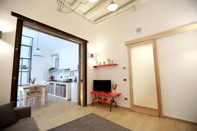 a living room with a sliding glass door and a kitchen at La Casetta delle Scienze Suite in Palermo