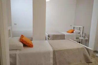 two beds in a room with orange pillows on them at Casa Costanzo in Capaci