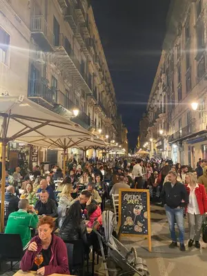 a crowd of people sitting at tables on a street at night at Cozy apartment near Palermo Cathedral in Palermo