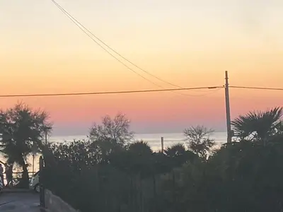 a sunset over the ocean with palm trees at FronteMare in Palermo