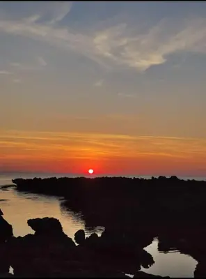 a sunset over the water with the sun in the sky at FronteMare in Palermo
