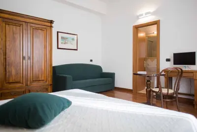 a bedroom with a bed and a couch and a desk at Hotel La Piazzetta in Castellammare del Golfo