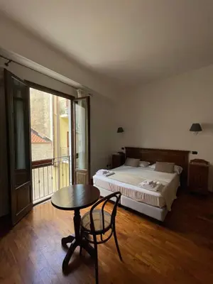 a bedroom with a bed and a table and a bed and a window at Hotel La Piazzetta in Castellammare del Golfo