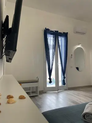 a room with a bed and a window with blue curtains at Casa Lella Holiday Boutique in Palermo