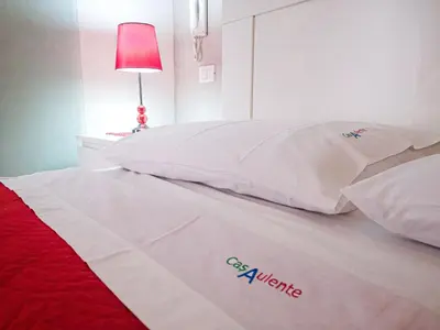 a bed with two white pillows and a red lamp at Casaulente in Alcamo