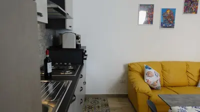 a living room with a yellow couch and a kitchen at Stella di Mare in Balestrate