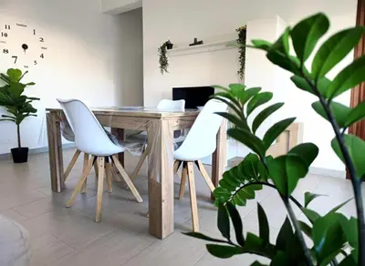 a dining table with white chairs in a room with plants at Dove il mare incontra il Relax!Ampio appartamento Conchiglia Home in Alcamo Marina
