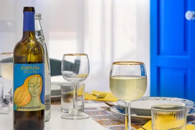 a bottle of white wine sitting on a table with glasses at CoralBay San Vito lo Capo - Appartamento in San Vito lo Capo