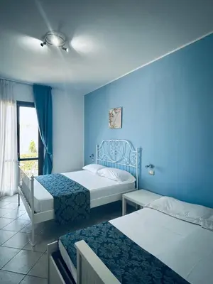 two beds in a room with blue walls at Hotel Achibea in San Vito lo Capo