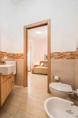a bathroom with a sink and a toilet and a bed at Villa DellOmbra in Alcamo