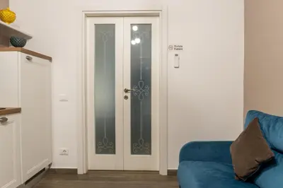 a glass door in a room with a blue couch at Vittorio Emanuele Charming Central Flats in Palermo