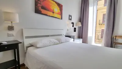 a white bedroom with a white bed and a window at Palermo Amari in Palermo