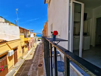 a balcony with a table with a red rose in a vase at Casa vacanze A&G in Castellammare del Golfo
