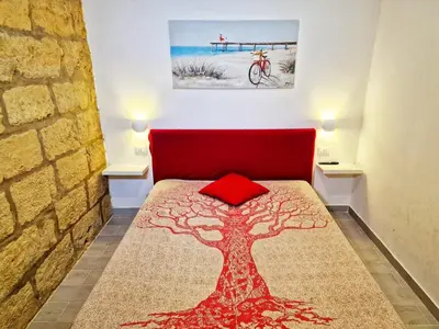 a bedroom with a red bed with a tree on it at Casa vacanze A&G in Castellammare del Golfo
