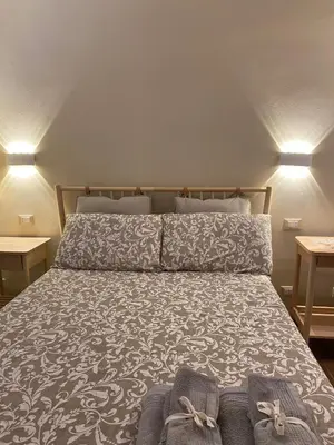 a bed in a room with two tables at Chirone Room in Mondello