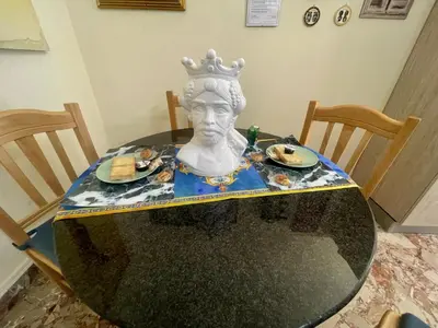 a table with a bust of a head with plates of food at Maya's Apartment close to Ballarò Market and Central station in Palermo