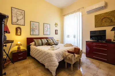 a bedroom with a large bed and a television at Hola Cathedral House Porta di Castro in Palermo