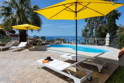a pool with two yellow umbrellas and a table and chairs at Villa Mediterraneo in Altavilla Milicia
