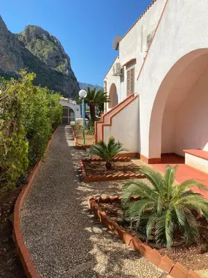 a walkway next to a building with palm trees at Villa San Vito Bay in Macari