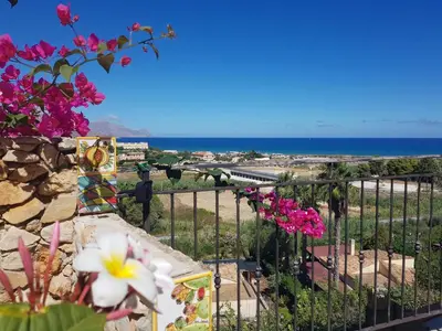 a view of the ocean from a balcony with flowers at Villa delle Pomelie - Castellammare del Golfo in Alcamo