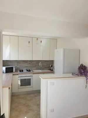 a kitchen with white cabinets and a white refrigerator at Dancing Apartment in Castelluzzo