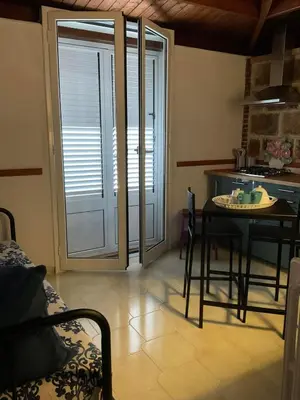 a living room with a table and a kitchen with a sliding glass door at la Casetta di Laura in Terrasini