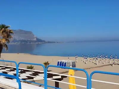a beach with a bunch of chairs and the ocean at La Dependance delle Mimose in Isola delle Femmine