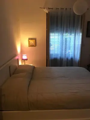 a bedroom with a white bed with a lamp and a window at Casa Delizia in Lido di Mondello