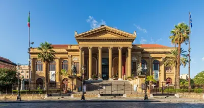 a large building with palm trees in front of it at Le Stanze dei Tesori - Luxury Rooms in Palermo