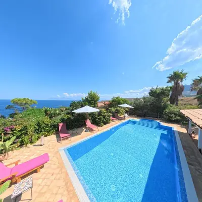 a patio with a table and chairs and a pool at Stunning Seafront Villa in Scopello Pool & Jacuzzi in Scopello
