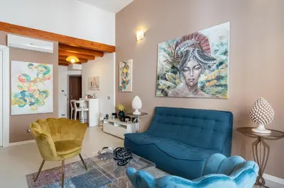 a living room with a blue couch and a painting on the wall at Suite San Sebastiano by DomuSicily in Palermo