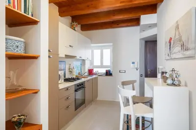 a kitchen with white walls and wooden beams at Suite San Sebastiano by DomuSicily in Palermo