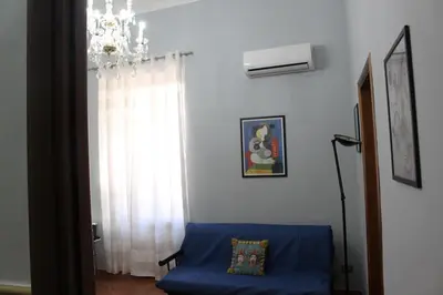 a living room with a blue couch and a chandelier at Himera Holiday in Palermo