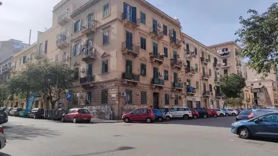 a large building with cars parked in a parking lot at Himera Holiday in Palermo
