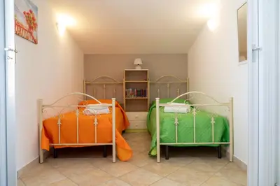 a bedroom with two beds and a book shelf at Garden Voyages Balestrate in Balestrate