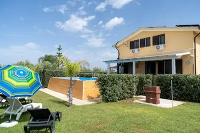 a house with a yard with chairs and an umbrella at Garden Voyages Balestrate in Balestrate