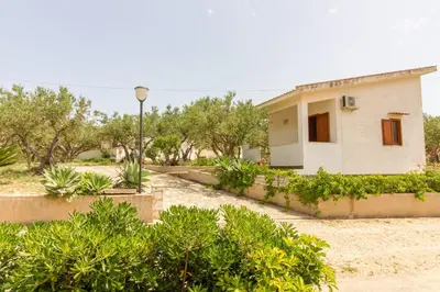 a house in the desert with trees and a street light at Casale la Macina Residence Scopello in Scopello