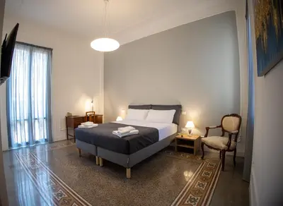 a bedroom with a bed and a chair at Petrarca Suite in Palermo