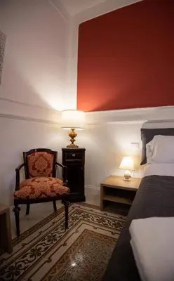 a bedroom with a bed and a chair and a lamp at Petrarca Suite in Palermo