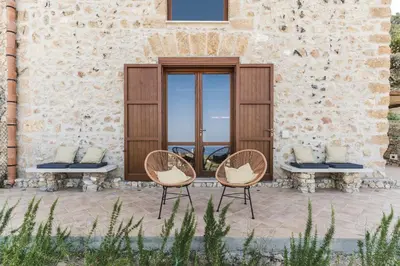 two chairs sitting in front of a building with a door at Alla Riserva - Villa Riserva dello Zingaro - Scopello in Scopello