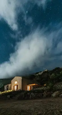 a small brick building on the beach at night at Alla Riserva - Villa Riserva dello Zingaro - Scopello in Scopello