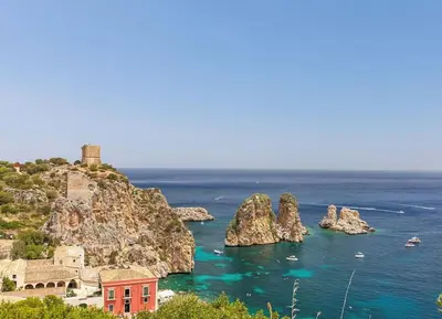 a view of the ocean with a red house on a cliff at Cala Bianca (The One&Only) in Castellammare del Golfo