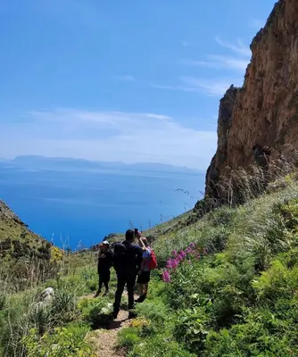 a group of people walking on a mountain trail at Cala Bianca (The One&Only) in Castellammare del Golfo