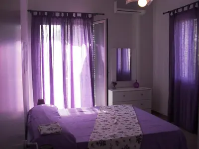 a bedroom with a bed and a window with purple curtains at La Casa sul Mare in Balestrate