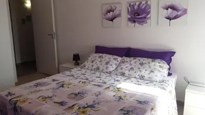 a bedroom with a bed with purple sheets and purple flowers at La Casa sul Mare in Balestrate