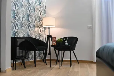 a living room with two black chairs and a lamp at Boscò Suites in Carini