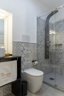 a bathroom with a toilet and a glass shower at Peonia Boutique Apartments in Palermo