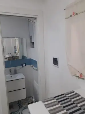 a small white bathroom with a sink and a mirror at Oneto Apartment in Palermo