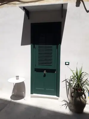 a green door on a white building with a table at Oneto Apartment in Palermo